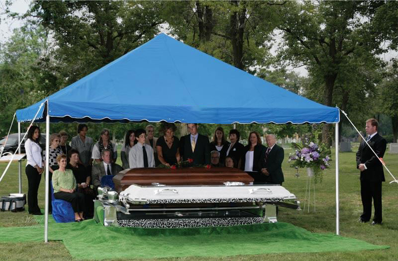 Photo of people at a funeral service under a tent outside